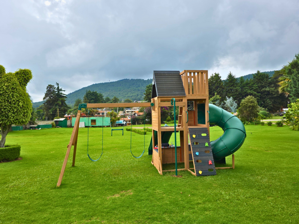 Area de juegos de tobogán y cabaña de madera