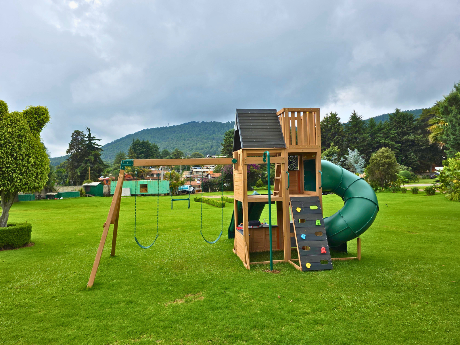 Area de juegos de tobogán y cabaña de madera